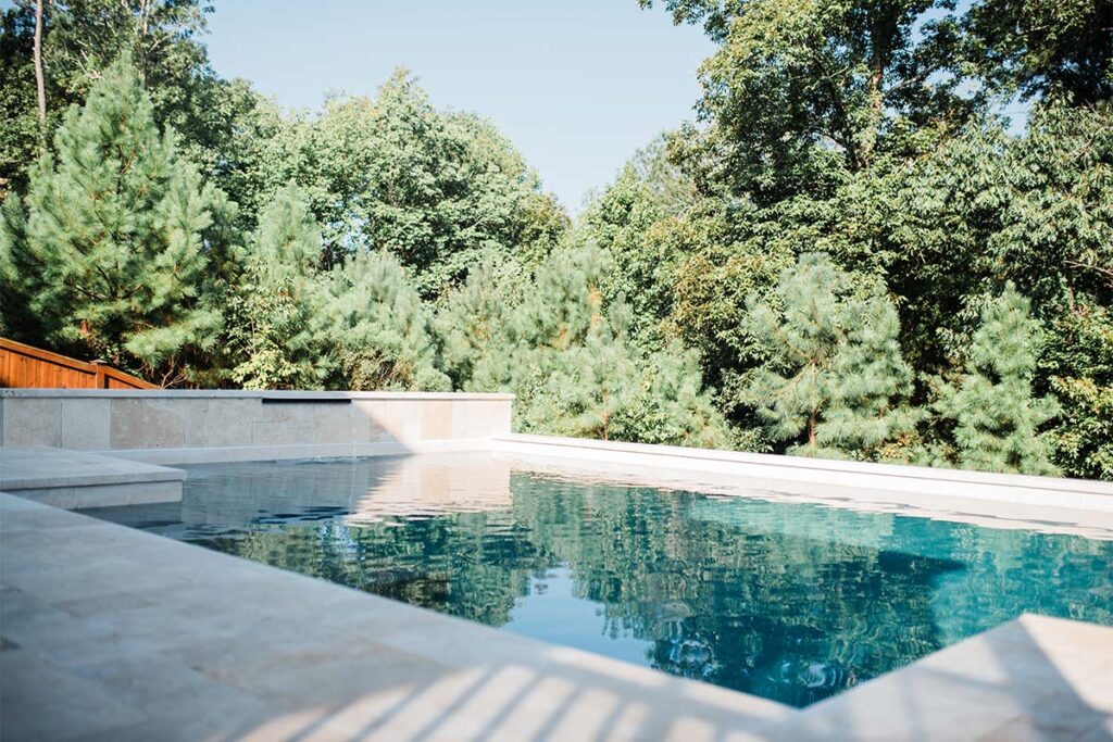 Wide view of Contemporary Durham concrete pool with forest in the background