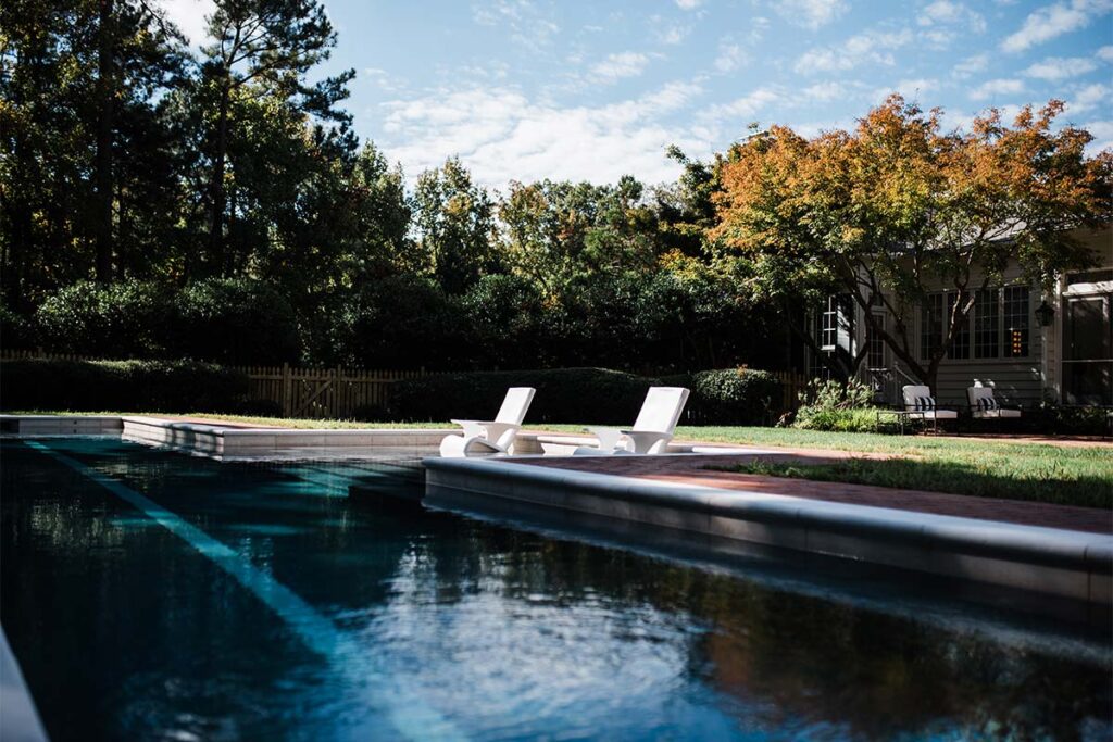 Wide view, ground level view of History Chapel Hill Pool with two pool chair in the center